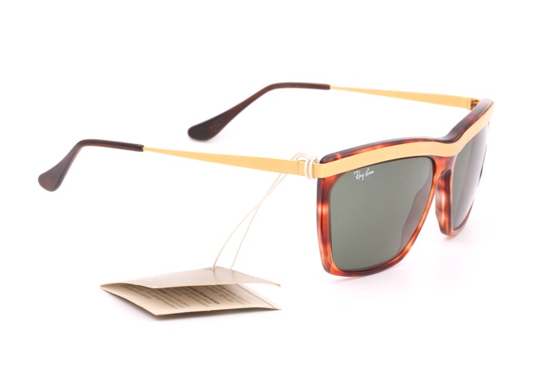 May include: Tortoise shell and gold Ray-Ban sunglasses with green lenses. The sunglasses have a gold metal band across the top of the frame.