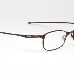 May include: Brown metal frame eyeglasses with clear lenses. The frame has a thin, sleek design.