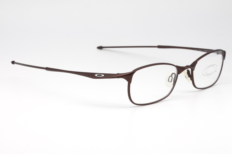 May include: Brown metal frame eyeglasses with clear lenses. The frame has a thin, sleek design.