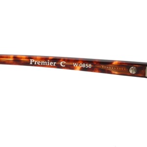 May include: Close-up of the tortoiseshell frame of a pair of sunglasses. The frame has the text "Premier C W 0858" printed on it.