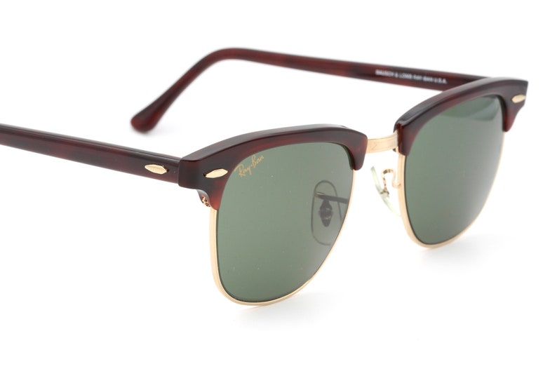 Może przedstawiać: Okulary przeciwsłoneczne Ray-Ban w brązowym kolorze imitującym pancerzyk ż&oacute;łwia z zielonymi szkłami i złotymi akcentami. Okulary mają klasyczny styl lotniczy.