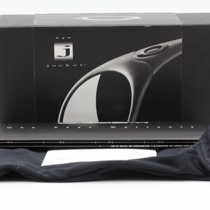 May include: Black box with the text "eye jacket" and a graphic of sunglasses. Includes a black drawstring bag, a warranty card, and a black case. The sunglasses are not visible.
