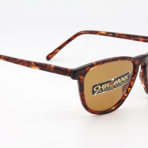 May include: Tortoiseshell-patterned sunglasses with brown lenses. The frames have a classic rectangular shape. The lenses have a sticker that reads "CHROMX COLOR CONTRAST TECHNOLOGY". The sunglasses are set against a white background.