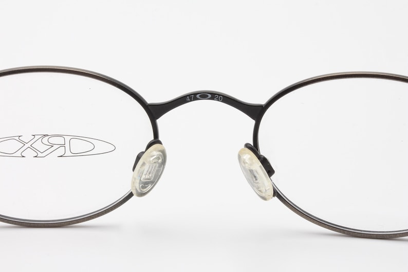 May include: Black round eyeglasses with clear lenses and a silver inscription that reads "47 20" on the bridge.