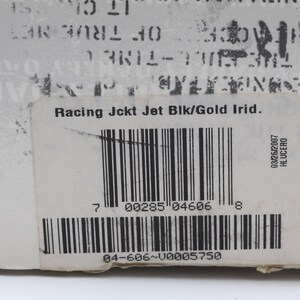 May include: A white label with black text that reads "Racing Jckt Jet Blk/Gold Irid." and a barcode. The barcode number is 00285 04606. The label also has a smaller label with the text "03/26/2007 HLUCERO".