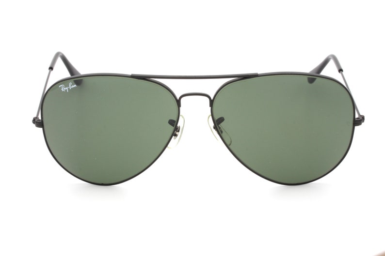 May include: Black aviator sunglasses with green lenses and Ray-Ban branding on the left temple.