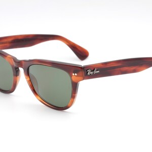 May include: Brown tortoiseshell Ray-Ban sunglasses with green lenses. The sunglasses have a classic aviator style frame.