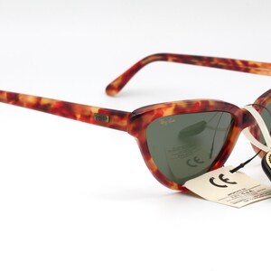 May include: Tortoiseshell Ray-Ban sunglasses with green lenses and a tag that reads "Original Bausch & Lomb".