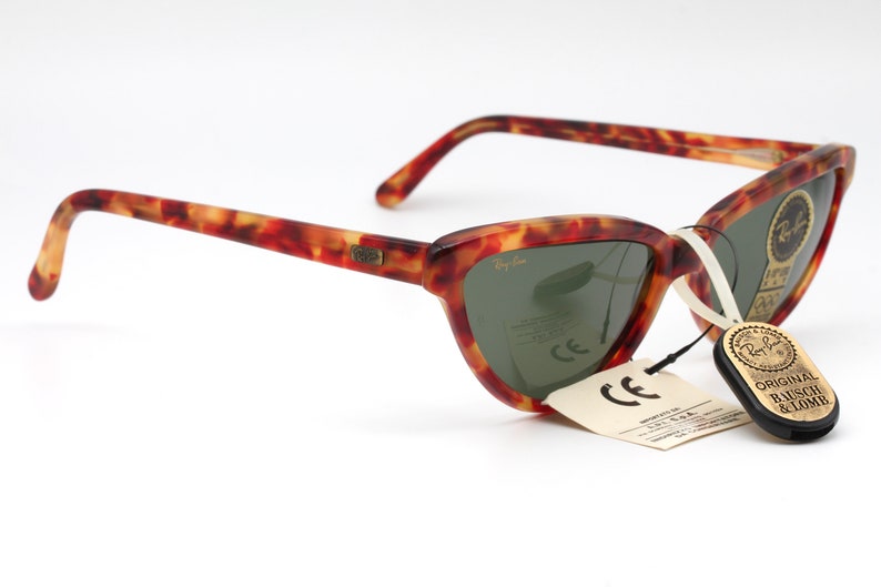 May include: Tortoiseshell Ray-Ban sunglasses with green lenses and a tag that reads "Original Bausch & Lomb".