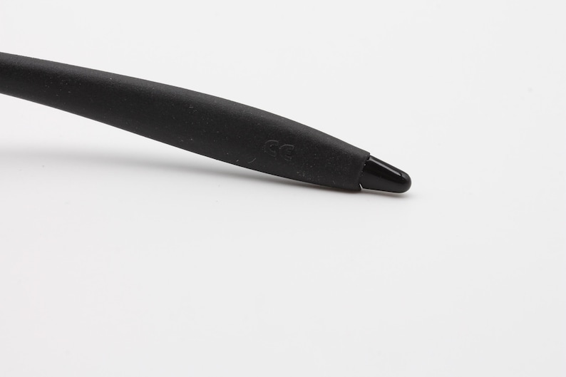 May include: Close-up of a black rubber temple tip with the letters "CG" embossed on the side.