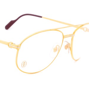 May include: Gold aviator style eyeglasses with a Cartier logo on the frame.