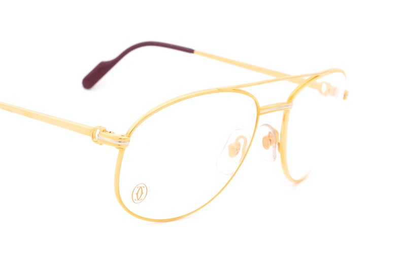 May include: Gold aviator style eyeglasses with a Cartier logo on the frame.