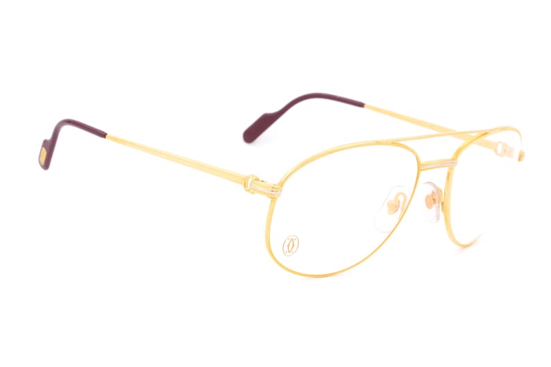 May include: Gold-tone aviator eyeglasses with clear lenses and a Cartier logo on the frame.