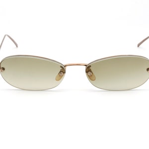May include: A pair of oval-shaped sunglasses with a brown metal frame and light brown lenses.