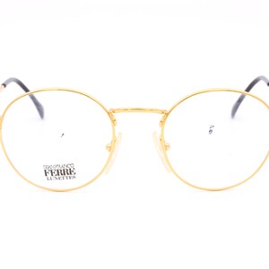 Può includere: Occhiali rotondi dorati con montatura nera e il testo "Gianfranco Ferre Lunettes" sulla lente sinistra.