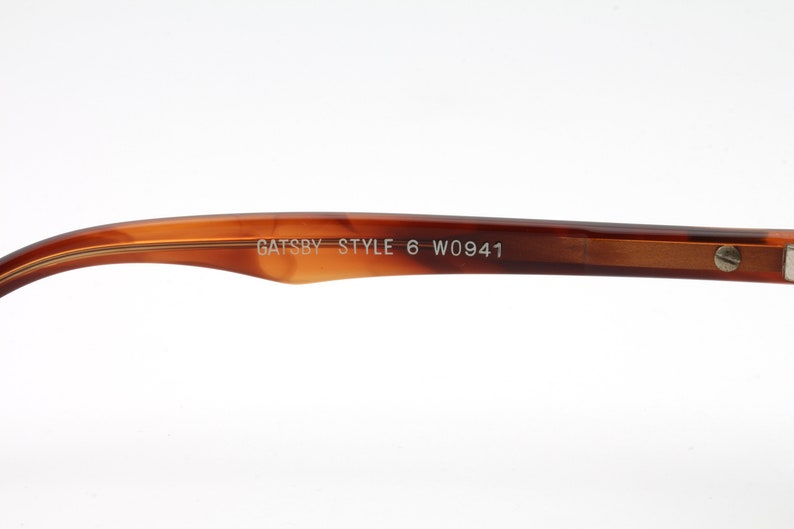 May include: Close-up of the brown tortoise shell temple arm of a pair of glasses. The arm is engraved with the text "GATSBY STYLE 6 W0941".