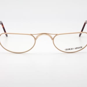Può includere: Occhiali da vista in metallo dorato con montatura rotonda e ovale. Il nome del marchio "Giorgio Armani" è stampato sulla stanghetta destra.