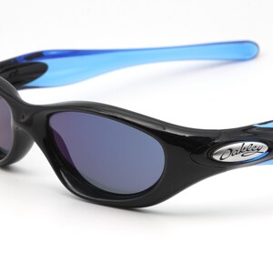 May include: Black Oakley sunglasses with blue arms and dark blue lenses. The Oakley logo is visible on the right arm.