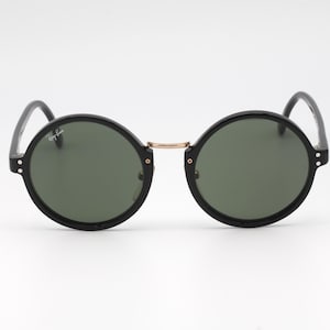 May include: Black round sunglasses with green lenses and a gold bridge.