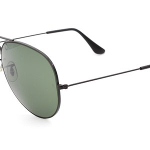 May include: Black aviator sunglasses with green lenses. The sunglasses have a thin metal frame.