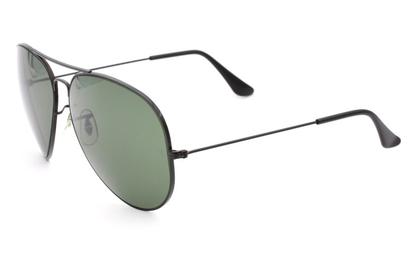 May include: Black aviator sunglasses with green lenses. The sunglasses have a thin metal frame.