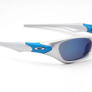 May include: Silver and blue sunglasses with a curved frame and blue lenses.