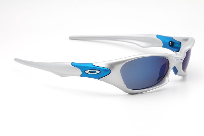 May include: Silver and blue sunglasses with a curved frame and blue lenses.