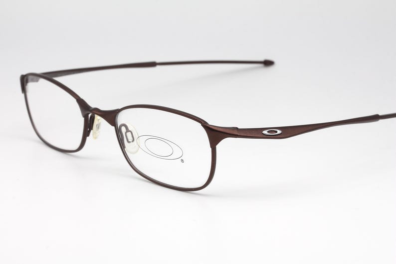 May include: Brown metal frame eyeglasses with clear lenses. The frame has a thin, wire-like design.