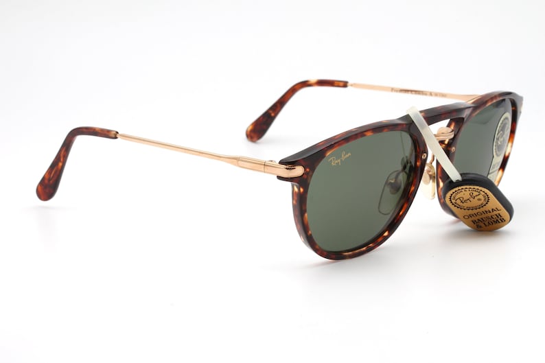 Op de afbeelding: Schildpad Ray-Ban zonnebril met groene glazen en gouden accenten. De zonnebril heeft een label met de tekst "Original Bausch & Lomb".