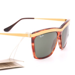 May include: Brown and gold Ray-Ban sunglasses with green lenses. The sunglasses have a tortoise shell frame with a gold trim.