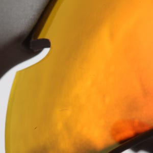 May include: Close-up of a yellow and orange tinted lens of a pair of sunglasses.