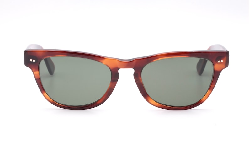May include: Tortoiseshell sunglasses with green lenses. The sunglasses have a classic, retro style.