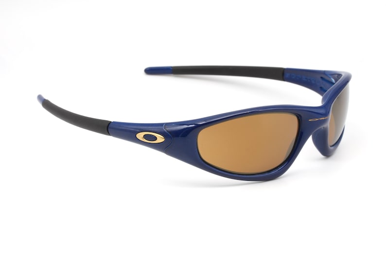 May include: Blue and gold framed sunglasses with brown lenses. The sunglasses have a sporty design.