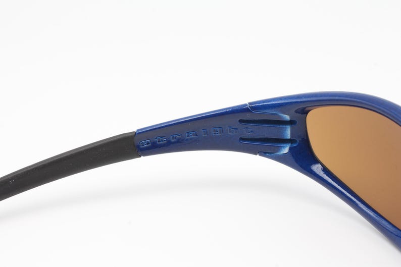 May include: Blue and black wraparound sunglasses with brown lenses. The sunglasses have the text "20 CE UV 400" printed on the side.