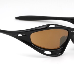 May include: Black wraparound sunglasses with brown lenses. The sunglasses have a sporty design with multiple vents and a curved frame.
