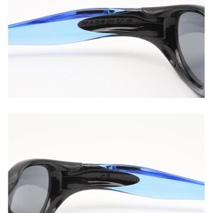 May include: Black sunglasses with blue and gray tinted lenses. The sunglasses have a black frame and blue and gray temples. The text "MADE IN U.S.A." is printed on the temple.
