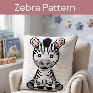 Peut inclure: Un coussin carré au crochet présentant un motif de zèbre pixélisé en noir, blanc et gris avec des oreilles intérieures roses. Le coussin a une bordure gris clair et une texture en grille. Le texte Zebra Pattern figure en haut.