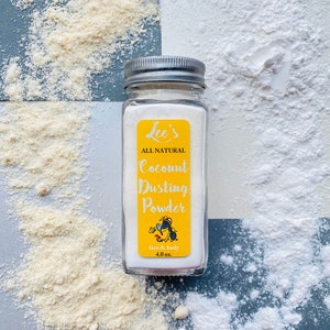 Puede incluir: Un frasco de vidrio transparente con tapa plateada, etiquetado como "Lee's ALL NATURAL Coconut Dusting Powder". La etiqueta amarilla presenta texto blanco y una hormiga de dibujos animados. El frasco contiene polvo blanco, con polvo disperso. El frasco es de 113 gramos.