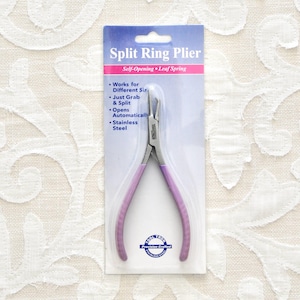 May include: Purple handled split ring pliers with a self-opening leaf spring. The packaging says "Split Ring Plier" and "Self-Opening Leaf Spring". It also lists features: "Works for Different Sizes", "Just Grab & Split", "Opens Automatically", and "Stainless Steel".