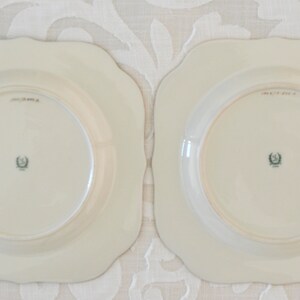 May include: Two white square-shaped plates with scalloped edges. The plates have a raised rim and a center well. The back of each plate has a green and black crest with the text "MADE IN USA".