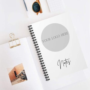 May include: A white spiral bound notebook with a grey circle in the centre that says "YOUR LOGO HERE" and the word "Notes" written in cursive below the circle.