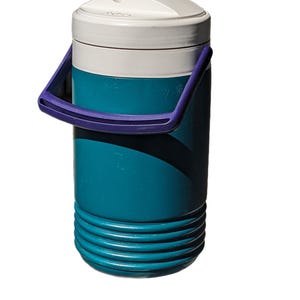 May include: A teal and white insulated water jug with a purple handle. The jug has a white lid with a small opening and a ribbed base. This beverage container is designed to keep drinks cold.
