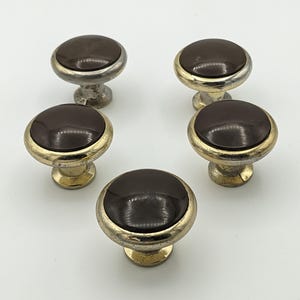 May include: Five brown ceramic cabinet knobs with gold trim and silver bases.