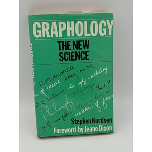 May include: A green book titled "Graphology: The New Science" with handwritten text on the cover. The text includes phrases like "Sentimentality of ideas stay away" and "This is matter of fact".
