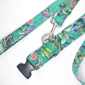 May include: A green and floral dog collar and leash set with a silver clasp. The collar has a black plastic buckle.