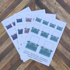 May include: A set of 10 typewriter stickers in various colors, including teal, pink, purple, and blue. The stickers feature a vintage typewriter design and are perfect for adding a touch of whimsy to planners, journals, and laptops. The stickers are sold by Nifty Notables Company, with a website and Instagram handle included on the sticker sheet.