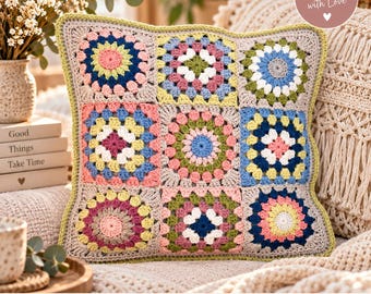 Könnte beinhalten: Ein quadratischer Kissenbezug aus Häkelarbeit mit einem Gitter aus neun bunten Granny Squares in Rosa, Blau, Gelb, Grün und Weiß, verbunden durch einen hellbeigen Garnrand. Die Kanten sind mit einer hellgrünen, wellenförmigen Häkelborte versehen.