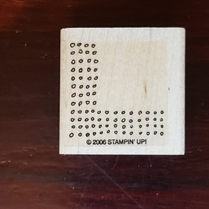 Peut inclure: Un tampon en bois avec un motif de petits cercles disposés en forme de L. Le tampon est étiqueté "©2006 STAMPIN' UP!"