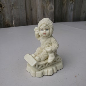 Snow Baby on Sled Toboggan Blue Eyes Rosy Cheeks holding a stocking Department 56