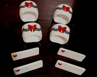 Servilleteros de cerámica vintage, tarjetas de lugar, guirnalda navideña y lazo rojo en caja